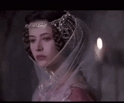 A Woman Wearing A Veil And A Crown Looks At The Camera . GIF
