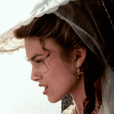 A Woman Wearing A Veil And Earrings Looks Down GIF