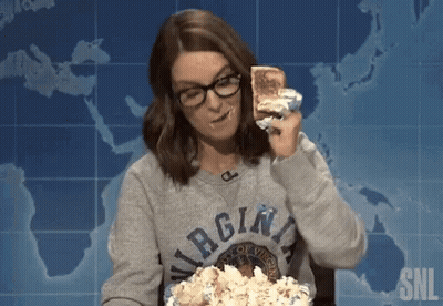 A Woman Wearing A Virgina Sweatshirt Is Eating A Sandwich And Popcorn GIF
