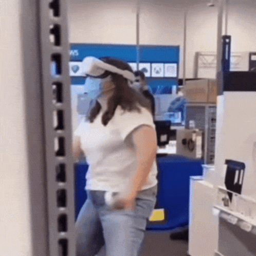 A Woman Wearing A Virtual Reality Headset Is Standing In A Store GIF