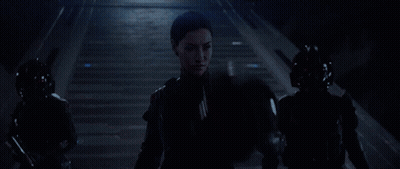 A Woman Wearing A Virtual Reality Headset Stands In A Dark Room GIF