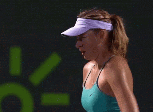 A Woman Wearing A Visor And A Green Tank Top GIF