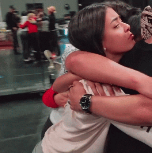 A Woman Wearing A Watch Is Hugging A Man GIF