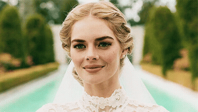 A Woman Wearing A Wedding Dress And Veil Smiles For The Camera GIF