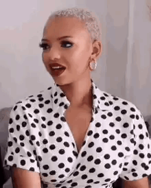 A Woman Wearing A White And Black Polka Dot Shirt Is Sitting On A Couch . GIF