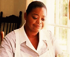 A Woman Wearing A White Apron Is Sitting At A Table With A Glass Of Water . GIF