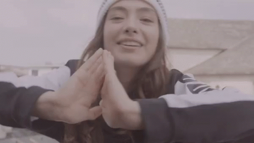 A Woman Wearing A White Beanie And A Black And White Sweatshirt With The Word Nike On The Sleeve GIF