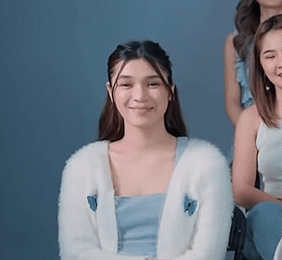 A Woman Wearing A White Cardigan With A Blue Butterfly On It Is Sitting Next To A Group Of Women . GIF