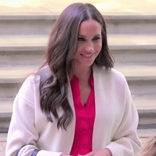 A Woman Wearing A White Coat And A Pink Shirt Is Smiling GIF