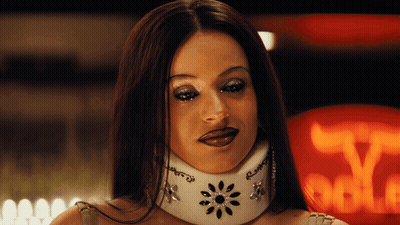A Woman Wearing A White Collar With Rhinestones On It Looks At The Camera GIF
