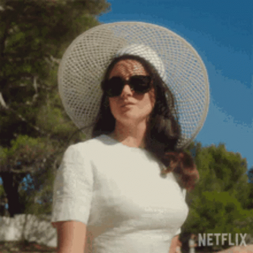 A Woman Wearing A White Dress And A White Hat And Sunglasses . GIF