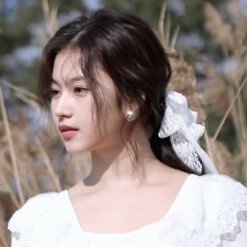 A Woman Wearing A White Dress With A Bow In Her Hair GIF