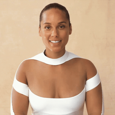A Woman Wearing A White Dress With A Very Plunging Neckline Smiles For The Camera GIF