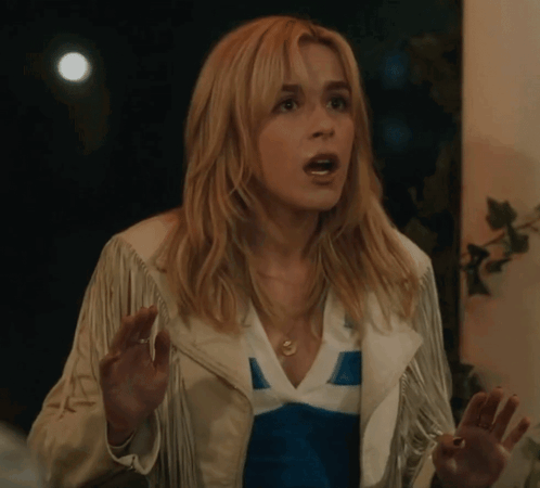 A Woman Wearing A White Fringed Jacket And A Blue And White Shirt Is Making A Surprised Face GIF