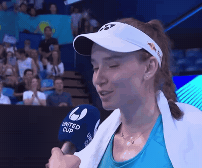 A Woman Wearing A White Hat And A Blue Shirt Is Talking Into A United Cup Microphone GIF