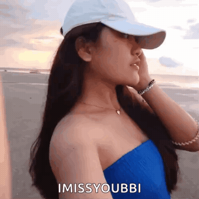 A Woman Wearing A White Hat And A Blue Top Says I Miss Youbbi GIF