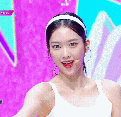 A Woman Wearing A White Headband And A White Tank Top Is Smiling GIF