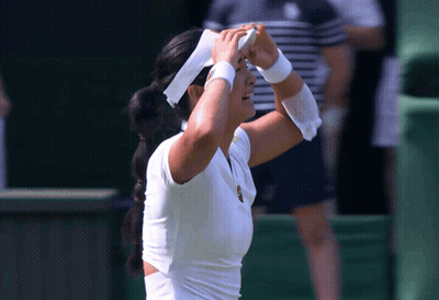 A Woman Wearing A White Headband And White Wristbands Wipes Her Forehead GIF
