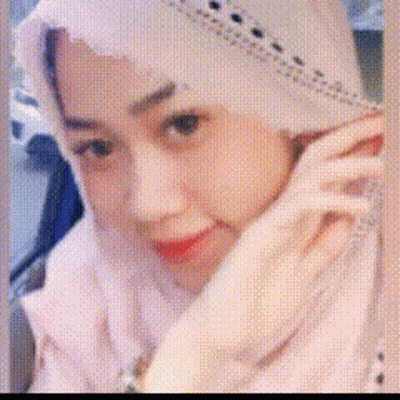 A Woman Wearing A White Hijab And A White Jacket Is Talking On A Cell Phone . GIF