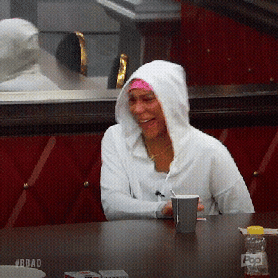 A Woman Wearing A White Hoodie Is Sitting At A Table With A Cup Of Coffee GIF