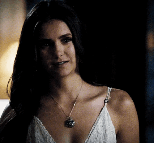 A Woman Wearing A White Lace Top And A Necklace GIF