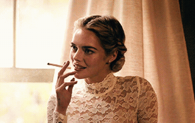 A Woman Wearing A White Lace Top Is Smoking A Cigarette GIF