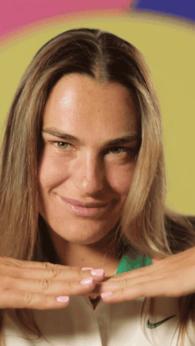 A Woman Wearing A White Nike Shirt Is Smiling With Her Hands On Her Chest GIF