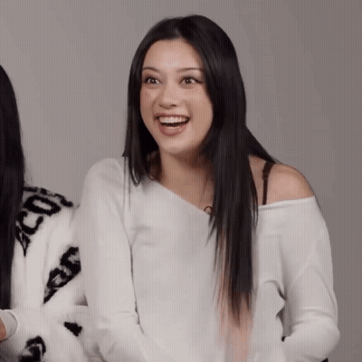 A Woman Wearing A White Off The Shoulder Sweater With The Letters Cc On It GIF