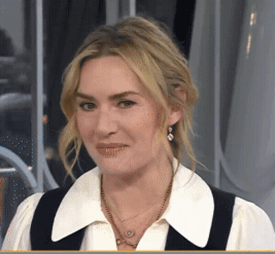 A Woman Wearing A White Shirt And A Black Vest Is Smiling GIF