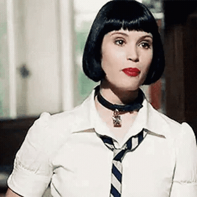 A Woman Wearing A White Shirt And A Blue And White Striped Tie Is Standing In Front Of A Window . GIF