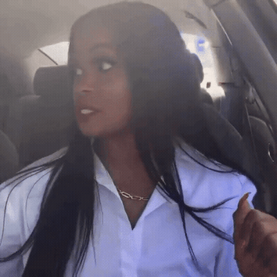 A Woman Wearing A White Shirt And A Gold Chain Necklace Is Sitting In A Car GIF