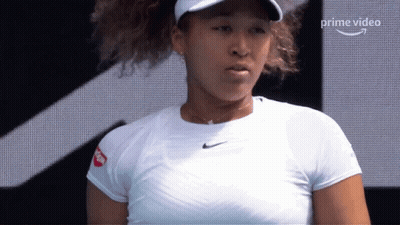 A Woman Wearing A White Shirt And A Hat Is Standing In Front Of A Screen That Says Prime Video On It GIF