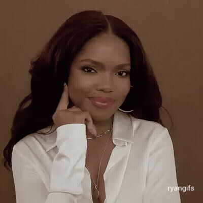 A Woman Wearing A White Shirt And A Necklace Is Smiling And Holding Her Hand To Her Chin . GIF