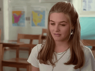 A Woman Wearing A White Shirt And A Necklace With A Cross On It GIF