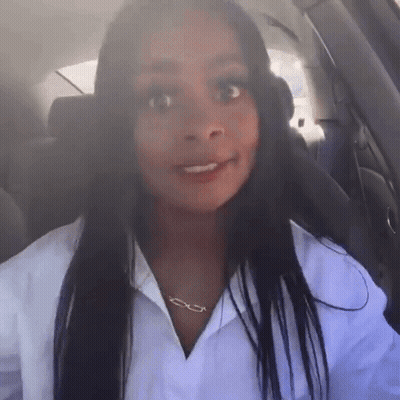 A Woman Wearing A White Shirt And A Necklace With The Letter E On It GIF
