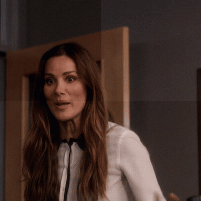 A Woman Wearing A White Shirt And Bow Tie Is Pointing At The Camera GIF