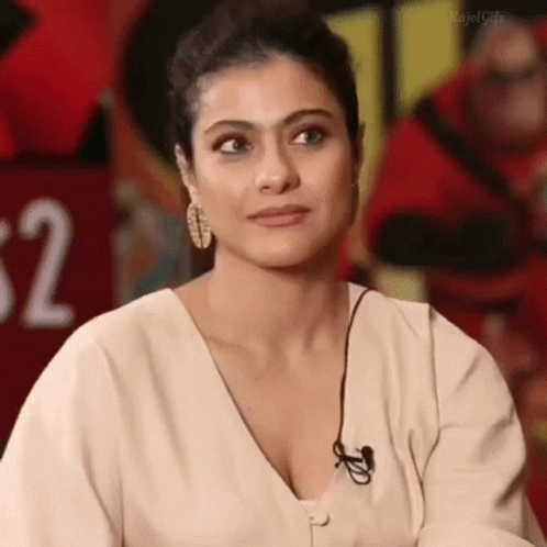 A Woman Wearing A White Shirt And Earrings Is Sitting In Front Of A Microphone . GIF