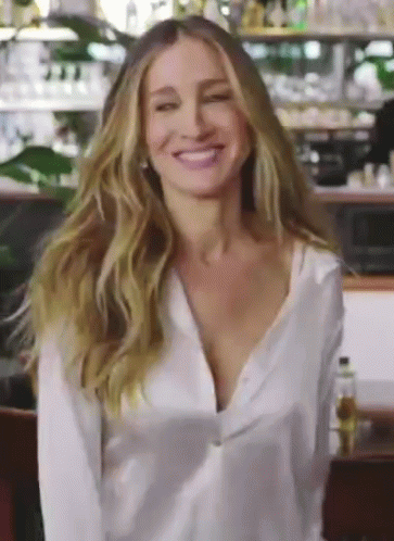 A Woman Wearing A White Shirt Is Smiling And Looking At The Camera GIF