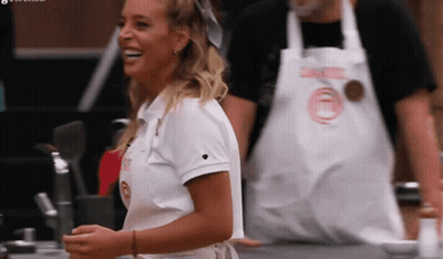 A Woman Wearing A White Shirt With A Heart On It Is Smiling In Front Of A Man Wearing An Apron GIF