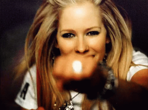 A Woman Wearing A White Shirt With The Letter A On It Is Pointing At The Camera GIF