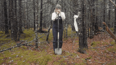 A Woman Wearing A White Sweater And Black Apron Has The Letter T On Her Apron GIF