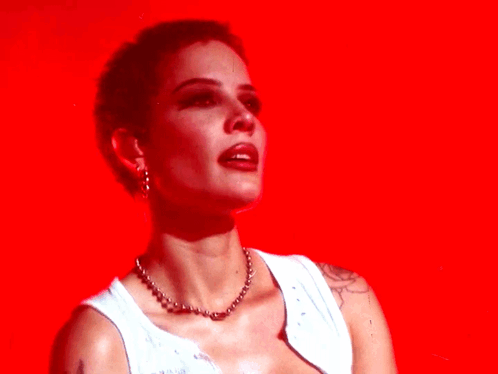 A Woman Wearing A White Tank Top And A Necklace Is Against A Red Background GIF