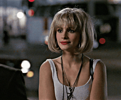 A Woman Wearing A White Tank Top With A Necklace Around Her Neck GIF