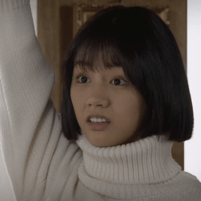 A Woman Wearing A White Turtleneck Sweater Looks Surprised GIF