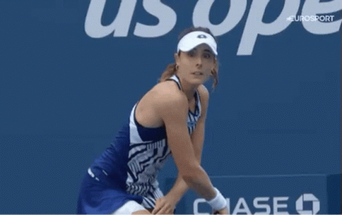 A Woman Wearing A White Visor Is Standing In Front Of A Sign That Says Uop GIF