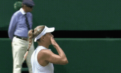 A Woman Wearing A White Visor Stands On A Tennis Court With Her Hand To Her Face GIF
