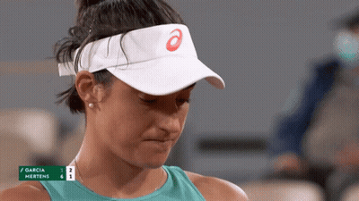 A Woman Wearing A White Visor With An Asics Logo On It Looks Down GIF
