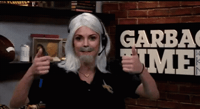 A Woman Wearing A Wig And A Headset Gives A Thumbs Up In Front Of A Garbage Time Sign GIF