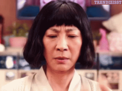 A Woman Wearing A Wig Is Making A Funny Face With The Words Trendizisst Written Above Her GIF