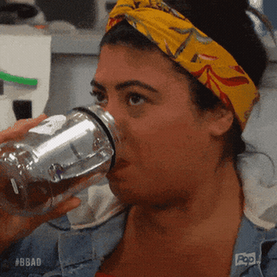 A Woman Wearing A Yellow Headband Is Drinking From A Clear Bottle .. GIF